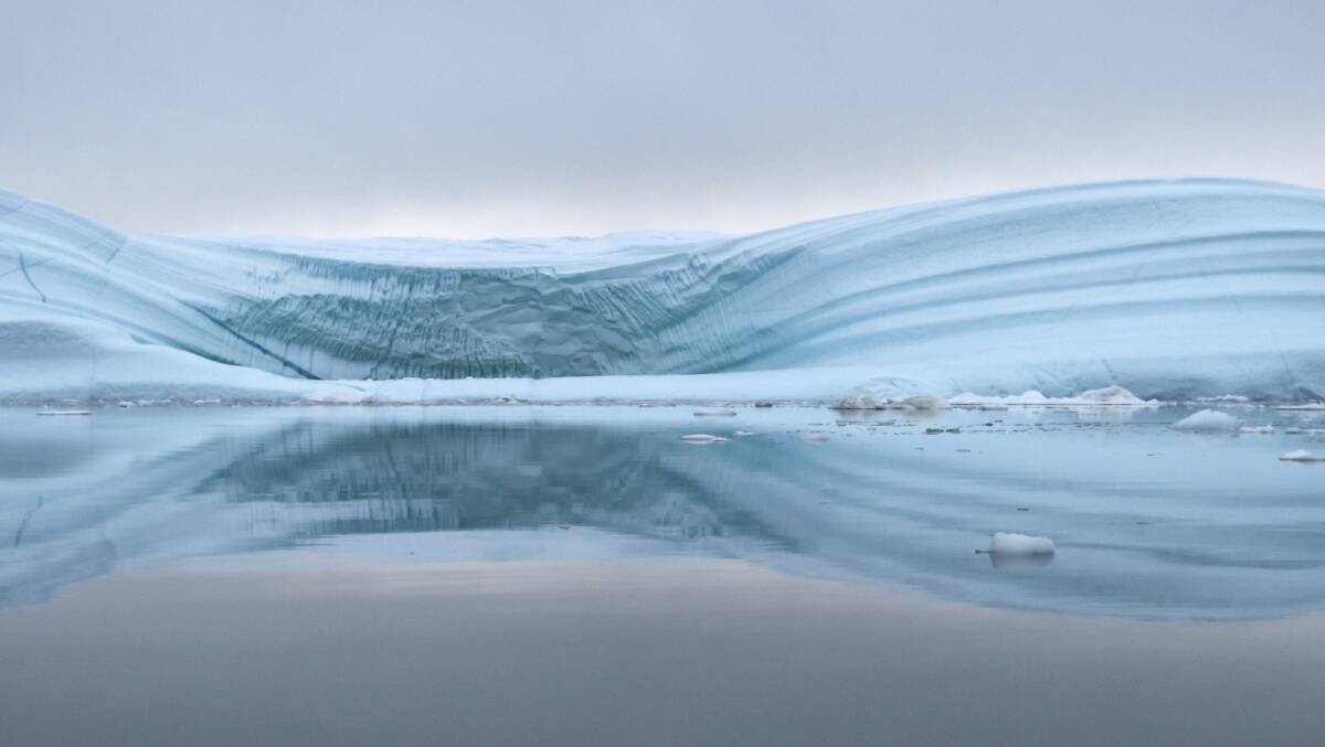 Icebergs reflected in the calm waters of Scoresby Sound. Picture: Getty Images