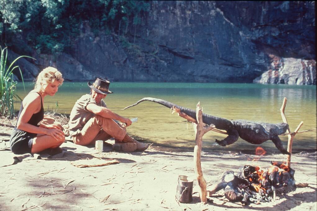 A goanna cooks on the open fire while Dundee and Charlton sit by the swimming hole. Picture supplied A goanna cooks on the open fire while Dundee and Charlton sit by the swimming hole. Picture supplied