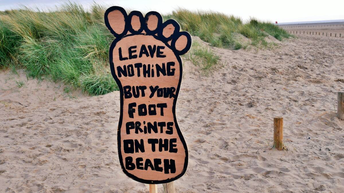 A sign on the beach reads 'leave nothing but your footprints on the beach'. Picture Unsplash/Vicky Hincks