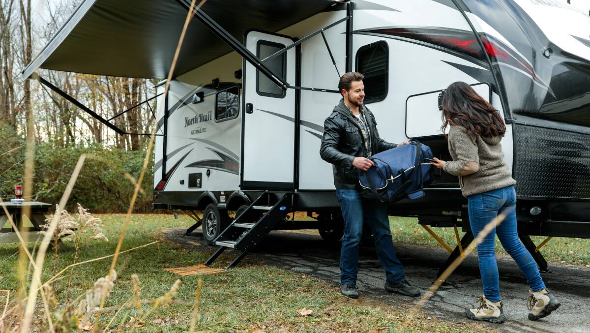 A couple is in the final stages of packing up a North Trail Ultra-Lite travel trailer for a road trip. Picture from Unsplash/Roadpass