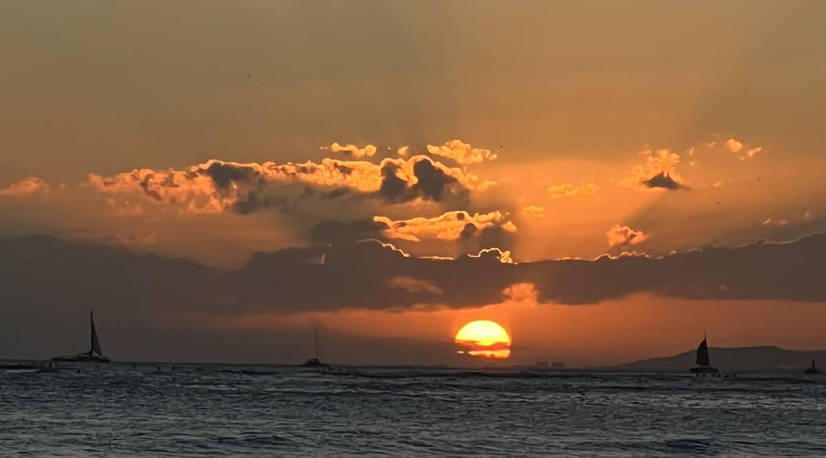 The sun sets over Waikiki Beach.