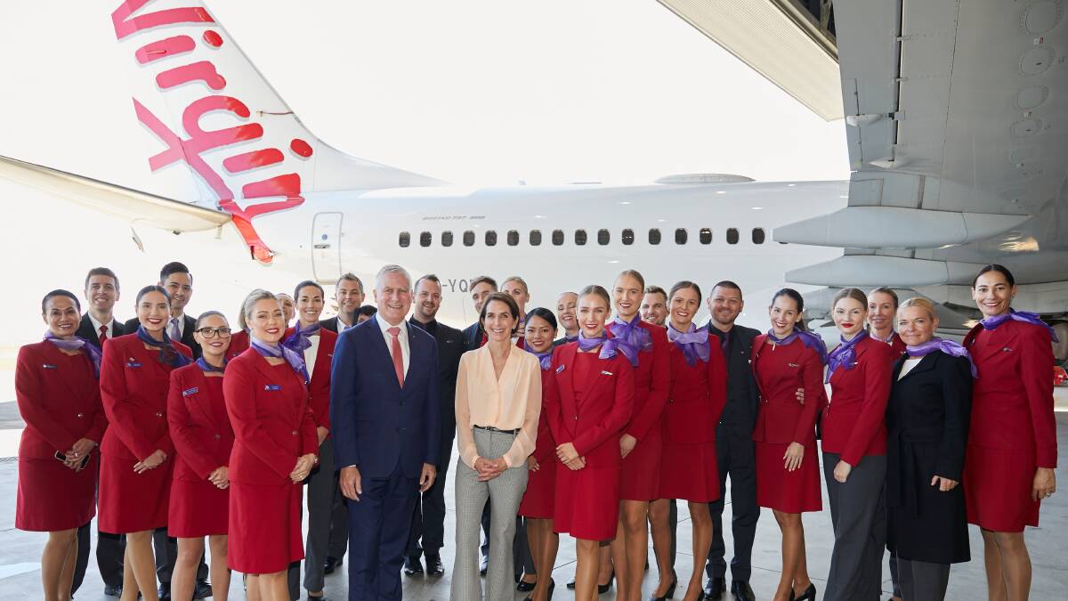 Virgin Australia staff stand in front of a Virgin Australia aircraft. Virgin Australia staff stand in front of a Virgin Australia aircraft.