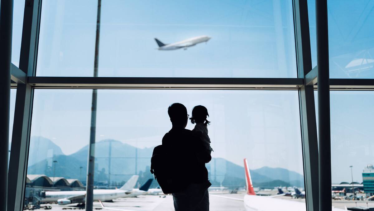 A parent with a child watch a plane taking off through an airport window. Picture: Supplied A parent with a child watch a plane taking off through an airport window. Picture: Supplied