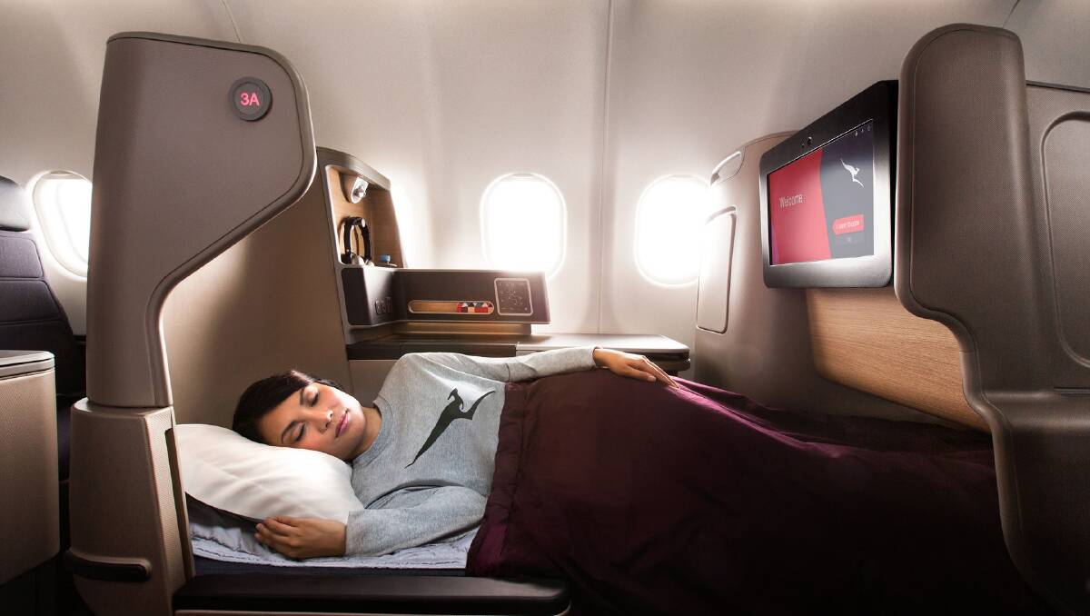 A woman sleeps in Qantas business class. A woman sleeps in Qantas business class.