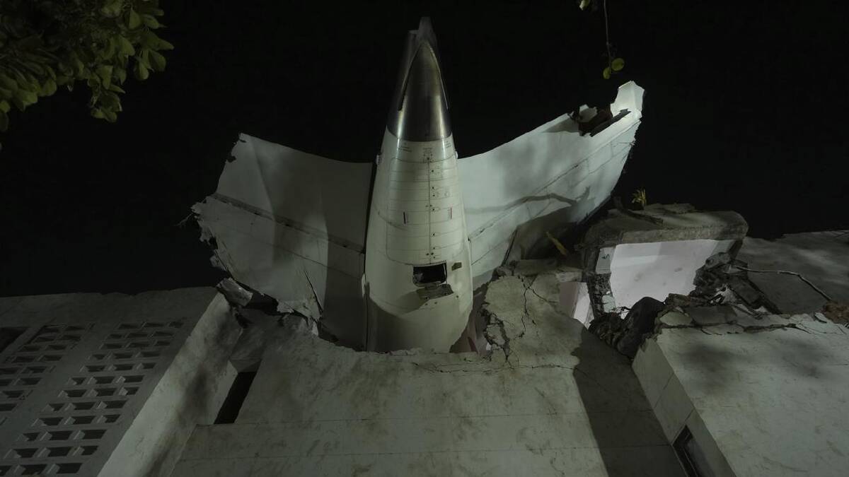 The tail of the passenger plane became stuck on top of the building it crashed into in Ahmedabad. (AP PHOTO)